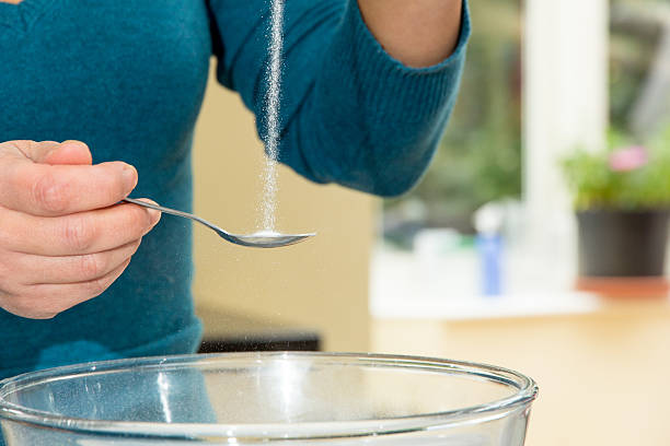 Woman measuring a spoonful of salt Woman measuring a teaspoonful of salt over a glass bowl teaspoon stock pictures, royalty-free photos & images