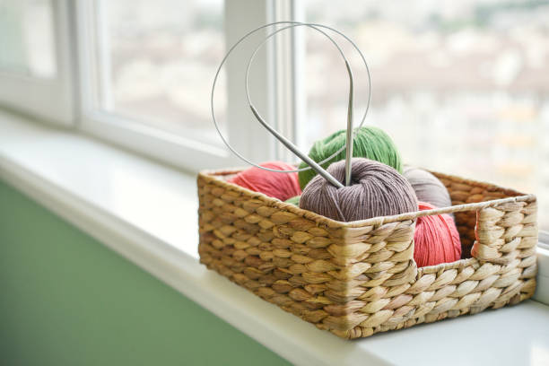 Colored yarn balls in wicker  basket on windowsill at home closeup