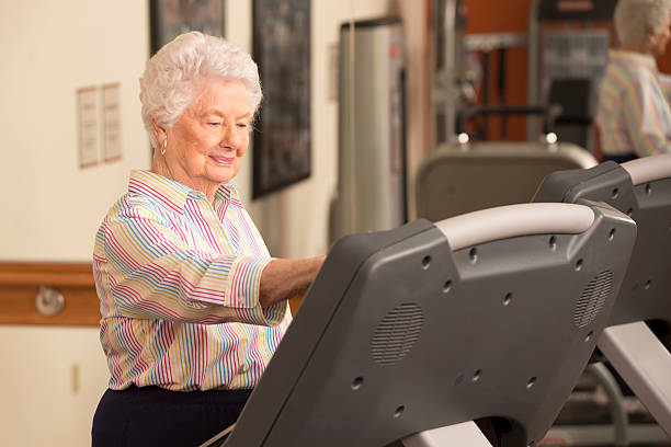 feliz mulher sênior exercitar-se na esteira na academia de ginástica - 65 70 age - fotografias e filmes do acervo