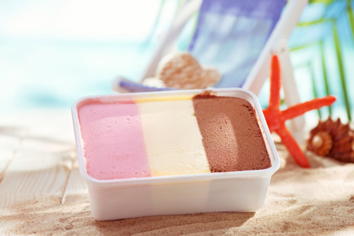 Neopolitan ice cream in plastic package on beach background