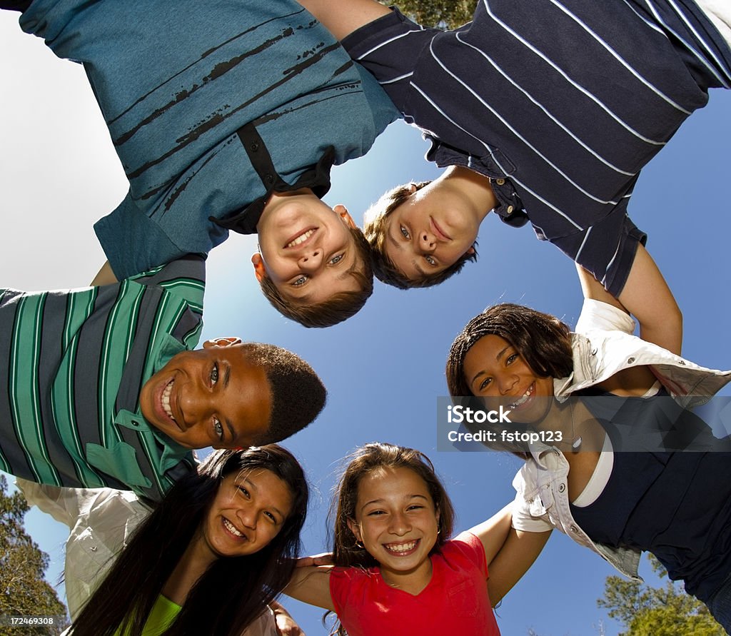 Relationships: Teenagers Smiling in a huddle against clear blue sky Teenagers: Smiling in a huddle against clear blue sky    Huddling Stock Photo