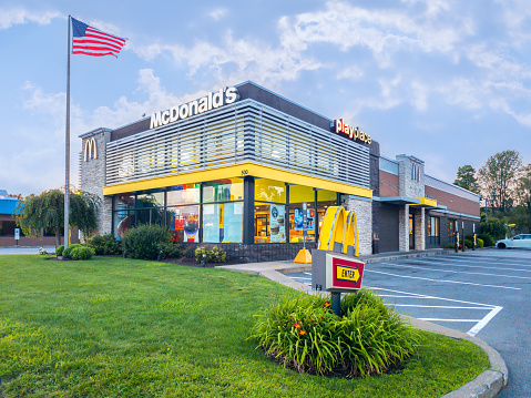 Whitesboro, New York - Aug 9, 2023: Landscape Close-up View of McDonald's Building Exterior with US Flag in Front.