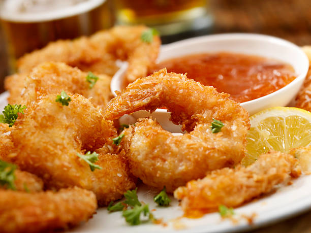 Coconut Shrimp "Coconut Jumbo Shrimp with fresh Parsley, Lemon, Dipping Sauce and a couple of beers - Photographed on Hasselblad H3D2-39mb Camera" Deep Frying stock pictures, royalty-free photos & images