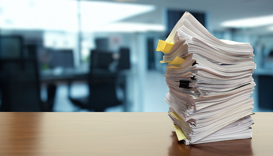 Large stack of documents on table with blurred office background