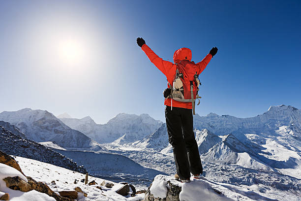 Woman trekking Mount Everest National Park, Nepal "Mount Everest National Park. This is the highest national park in the world, with the entire park located above 3000m. This park includes three peaks higher than 8,000 m, including Mt Everest. Therefore, most of the park area is very rugged and steep, with its terrain cut by deep rivers and glaciers." brightly lit winter season rock stock pictures, royalty-free photos & images