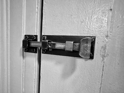 Plain modern silver door handle isolated on a solid gray door with key lock.