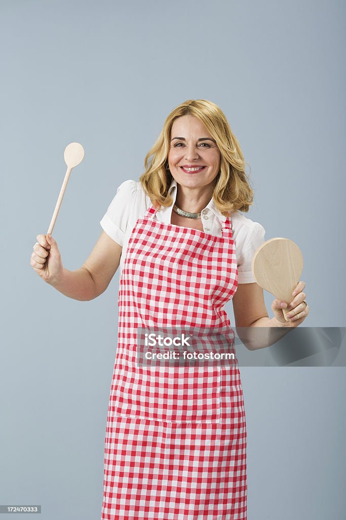 Delantal resistente mujer sosteniendo una cuchara de madera y tablón - Foto de stock de 40-49 años libre de derechos