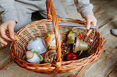 close up view on child hands holding basket with christmas decorations toys inside