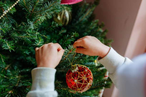 istock close up on child hands holding christmas tree decoration putting it on tree 1724715663