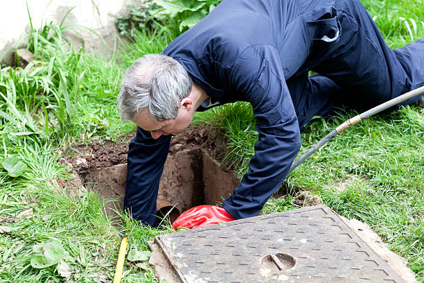 istock Man wearing overalls leaning into outdoor drain 172471985