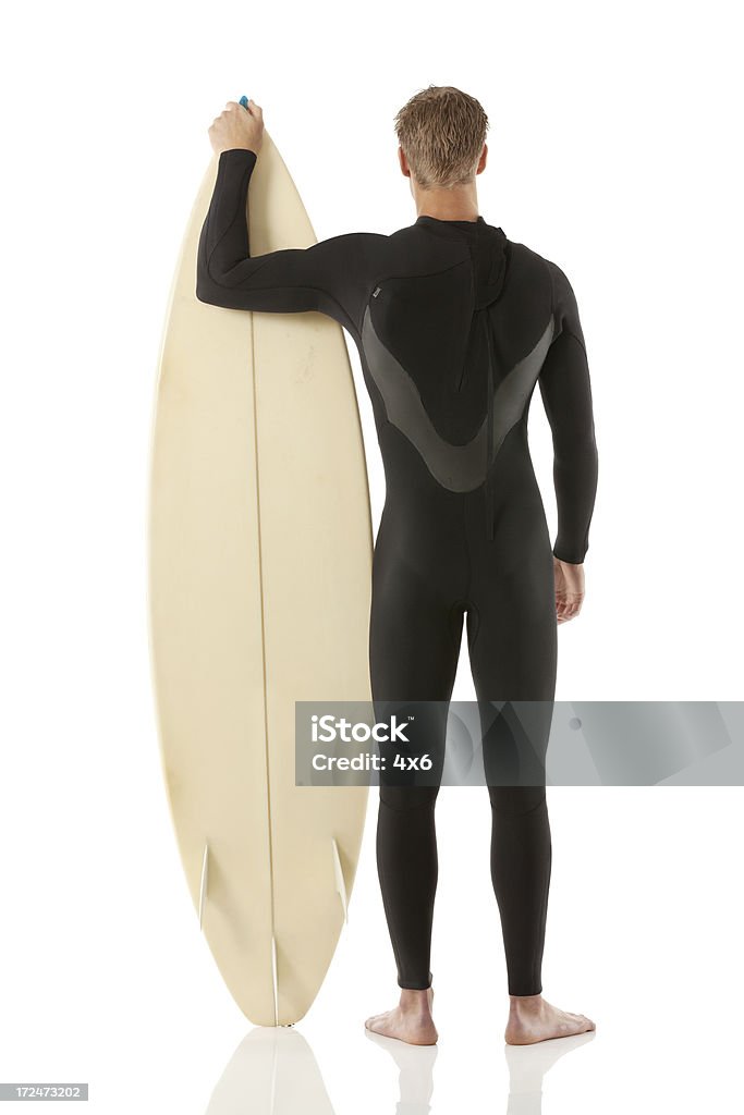 Vista posteriore di un uomo in piedi con la tavola da surf - Foto stock royalty-free di 18-19 anni