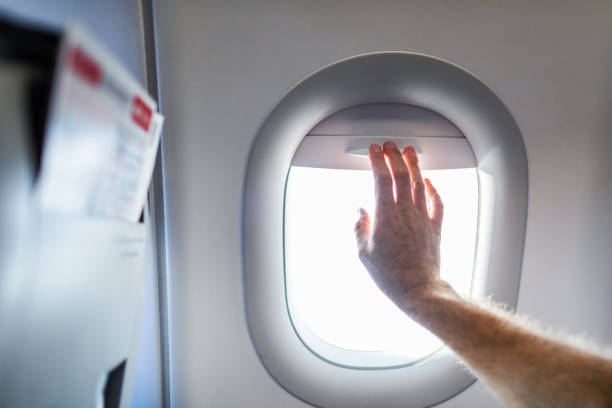 istock Close up of man's hand closing window blinds in airplane 1724732282