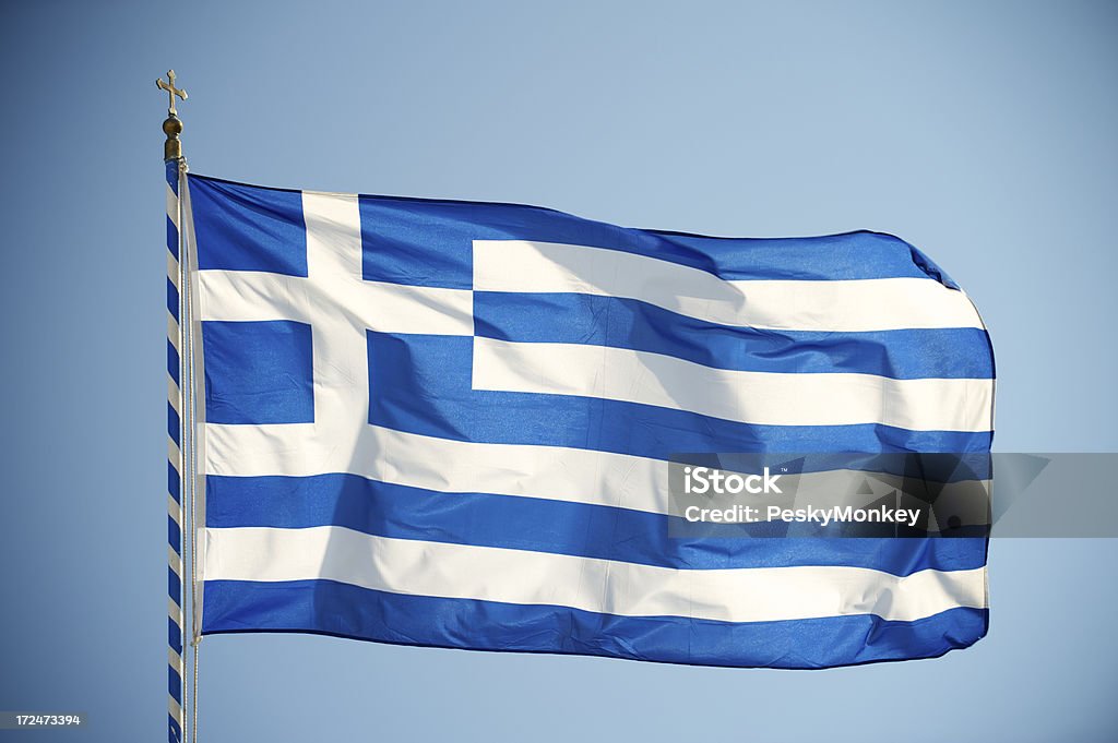 Greek Flag Backlit Horizontal Blue Sky on Flagpole Flag of Greece waving on flag pole in bright sun against a clear blue sky Back Lit Stock Photo