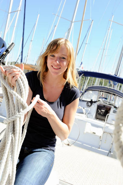 jeune femme coiling corde à bord d'un yacht voile - love smiling human settlement viewpoint photos et images de collection