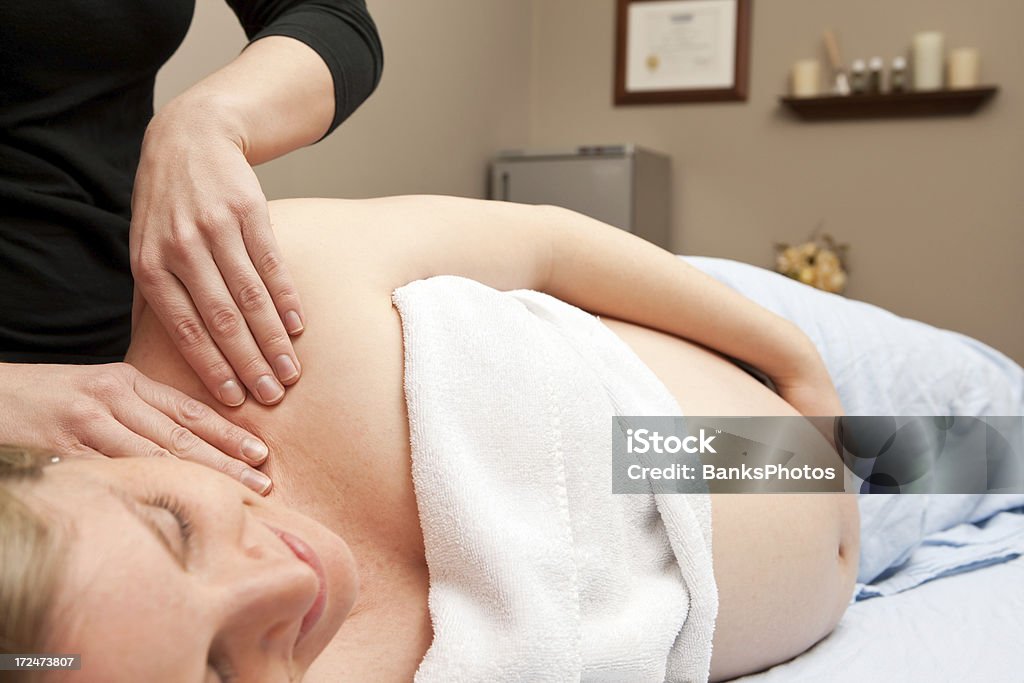 Donna incinta massaggio prenatale - Foto stock royalty-free di Incinta