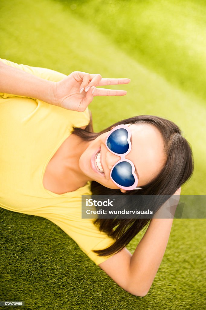 Asian girl lying on grass in park with sunglasses Asian girl lying on grass in park Adolescence Stock Photo