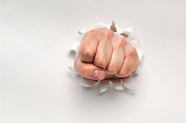 istock Fist punching through a ripped hole in a paper 172474093