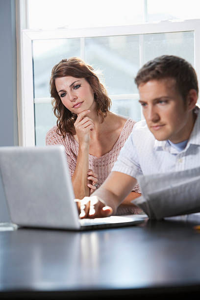 Home finances Couple at home paying bills.  Focus on woman (20s). Sc0601 stock pictures, royalty-free photos & images