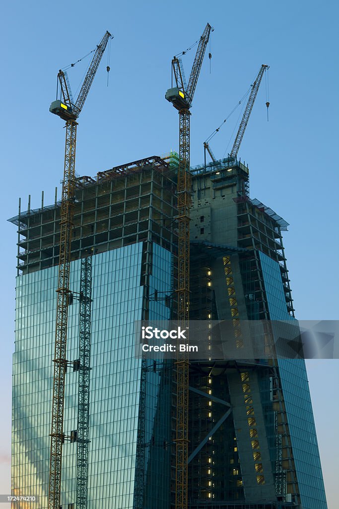 Arranha-céu em construção com grous ao anoitecer, Frankfurt, Alemanha - Foto de stock de Obra royalty-free