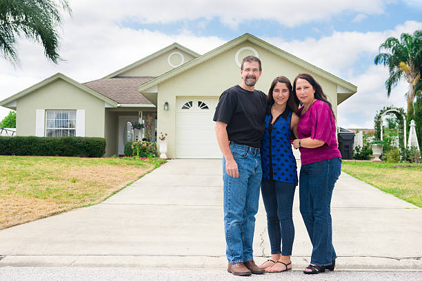 Small family poses in front of new home Happy family in front of their new home. in front of stock pictures, royalty-free photos & images