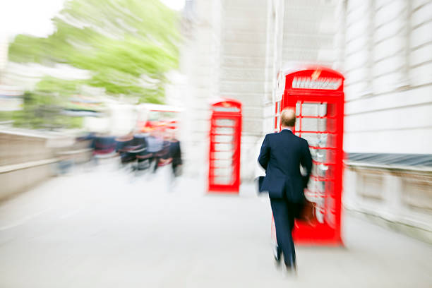 borrosa hombre de negocios caminando pasado cabinas telefónicas, londres, inglaterra - london england business telephone booth commuter fotografías e imágenes de stock