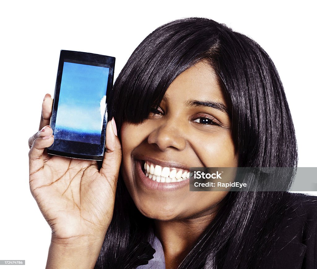 Look! Smiling woman shows blank cellphone screen. You add message This happily smiling young woman shows the blank screen of her android-operated mobile phone. The screen provides copy space for your image or message. Isolated. 20-29 Years Stock Photo