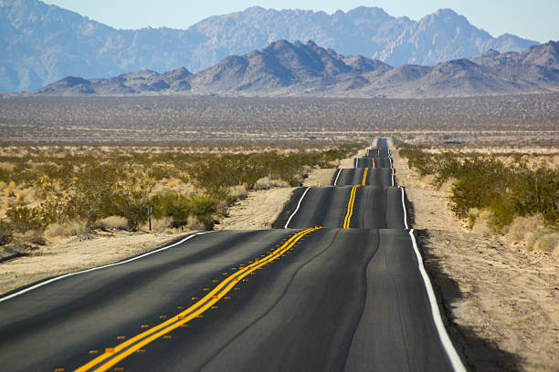 Desert Landscape with bumpy road A very bumpy road along a highway in the Southern California desert. bumpy photos stock pictures, royalty-free photos & images