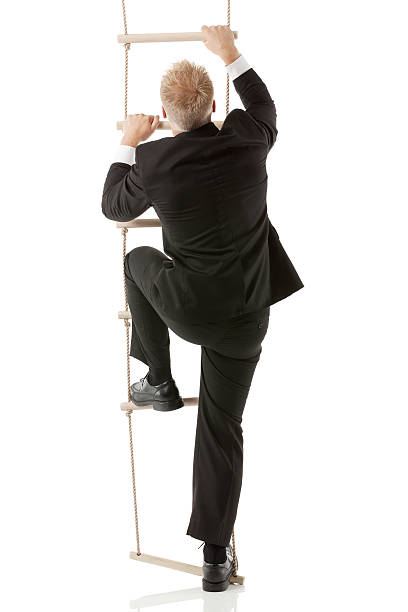 Businessman climbig a rope ladder stock photo