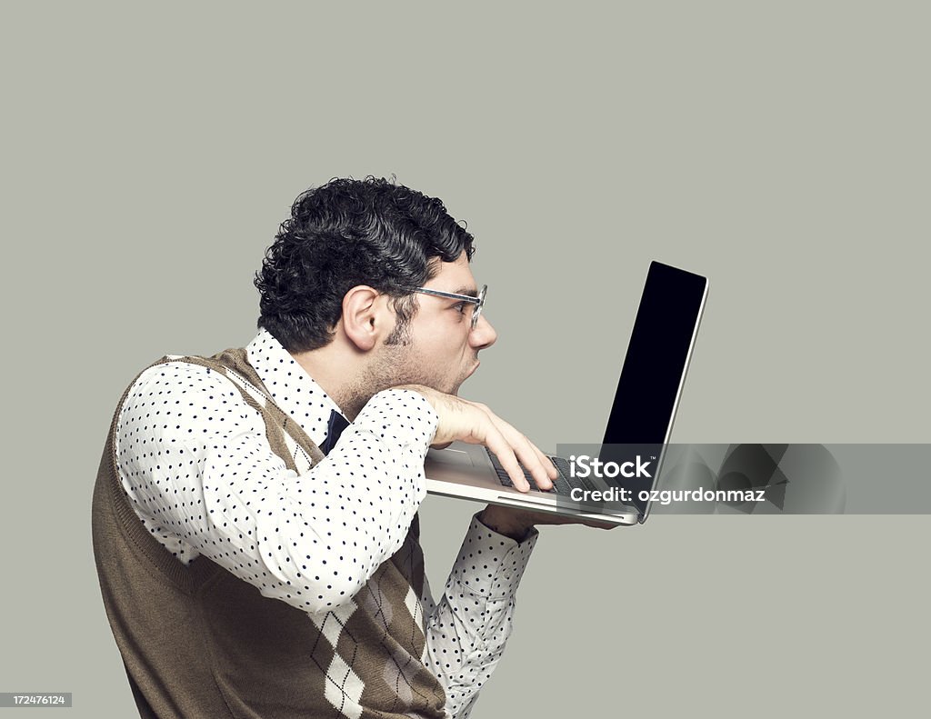 Nerdy young man using laptop Nerdy young man using laptop, studio shot Nerd Stock Photo