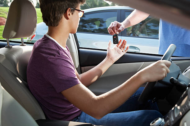 Teenage driver taking car keys Cropped view of teenage driver taking car keys from father. Focus on key. teenager boy driving stock pictures, royalty-free photos & images