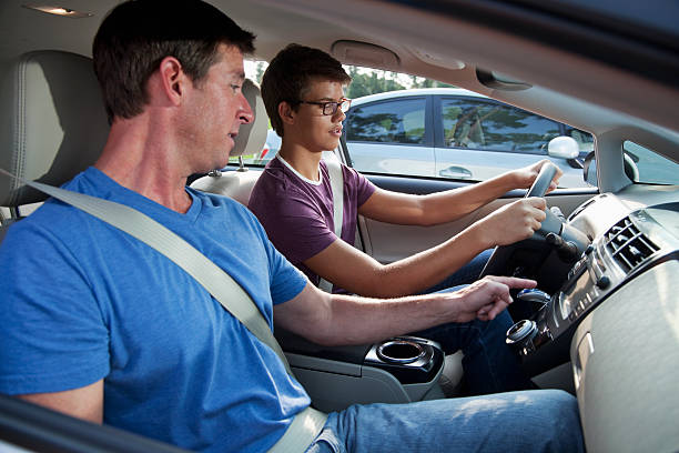 Teenager learning to drive Teenager (15 years) with driving instructor (40s). teenager boy driving stock pictures, royalty-free photos & images