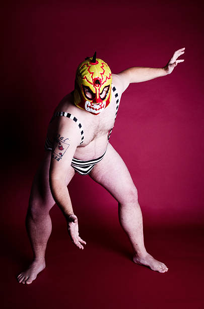 Young adult man wrestler  in a blue   tights  shows thumbs up on a black isolated  background