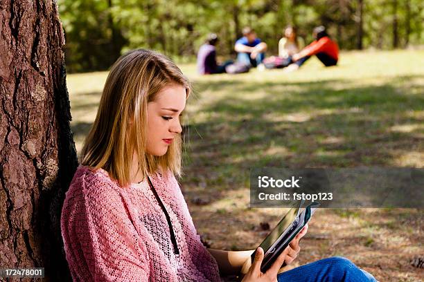 Foto de Tecnologia Feminino Teen Usa Tablet Digital Em Árvore Grupo Para Trás e mais fotos de stock de 16-17 Anos