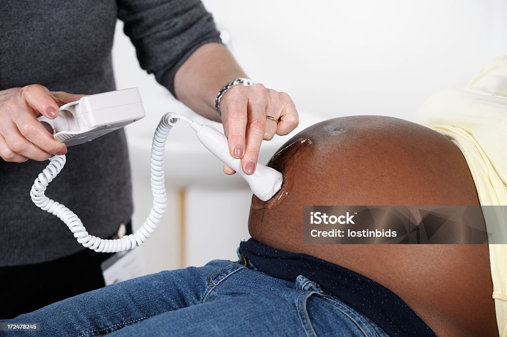 Afrikanische amerikanische Frau, die eine fötalen Doppler/pränatalen Bewertung - Lizenzfrei Hebamme Stock-Foto