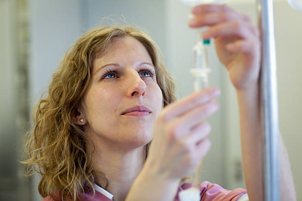 blond female nurse prepares an IV Drip female medical assistant is preparing an infusion infused oil stock pictures, royalty-free photos & images