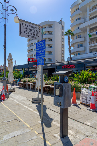 Coin-operated parking meter for car parking on the avenue next to the beach with a long stretch of dark sand in Larnaca, Cyprus.  September 2023.
