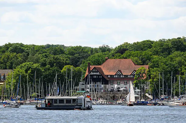 Harbor with sailing boats and old timbered house at Berlin Wannsee (Germany). In front a house boat.