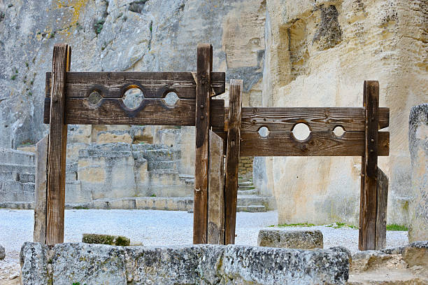 Stocks in medieval castle courtyard "Reproduction stocks, for public punishment of criminals, in a medieval courtyard at Les-Baux-de-Provence, France** sepia toned** The medieval Citadel and Chateau of Les-Baux-de-Provence seen through an ancient stone apertureMore like this" medieval restraints stock pictures, royalty-free photos & images