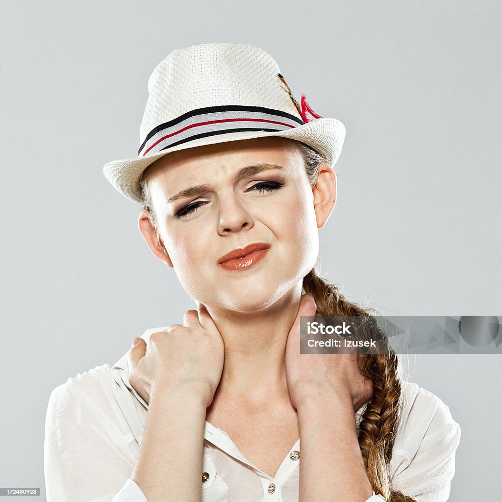 Neckache Portrait of young woman suffering from neckache. Studio shot on grey background. Neckache Stock Photo