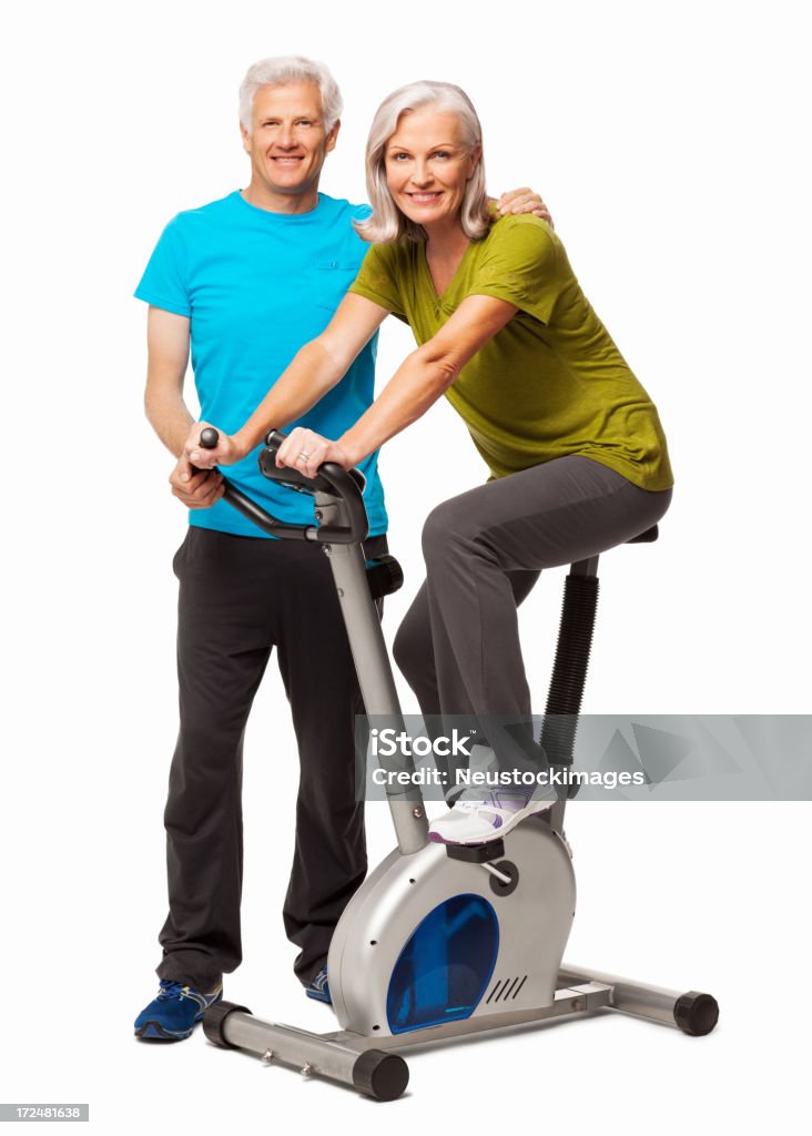 Adattarsi donna esercizio su esercizio bicicletta isolato - Foto stock royalty-free di 60-69 anni