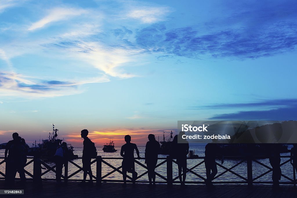 Group of People Enjoying Sunset on the Ocean People watching the sunset on the ocean Looking Stock Photo