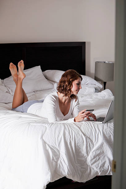 Woman shopping on the internet Woman (20s) laying in bed, shopping on the internet. Sc0601 stock pictures, royalty-free photos & images