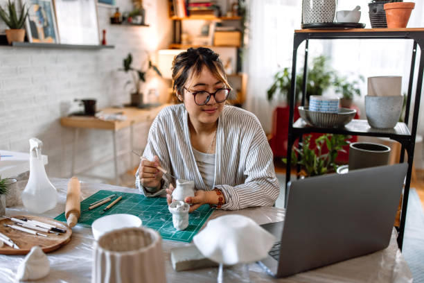 istock Young woman molding clay, using laptop for online learning 1724829470