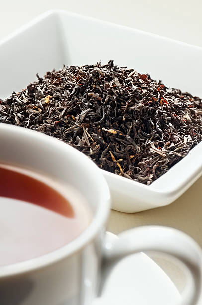Indian Assam tea leaves behind cup of tea