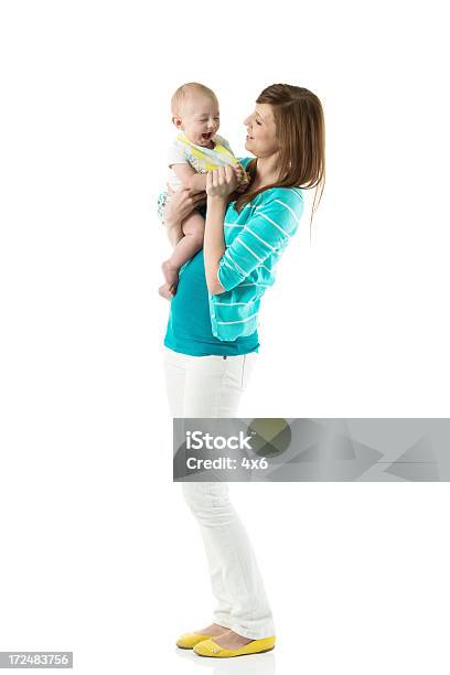 Sonriente Joven Madre Jugando Con Su Bebé Foto de stock y más banco de imágenes de Bebé - Bebé, Encuadre de cuerpo entero, Foto de estudio
