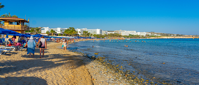 people walking on the sand by the sea on the beach in Ayia Napa district, close to the Mediterranean Sea, summer, September 2023.