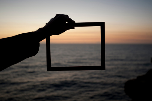 Business vision and creativity concept. Man holding a frame at sunrise