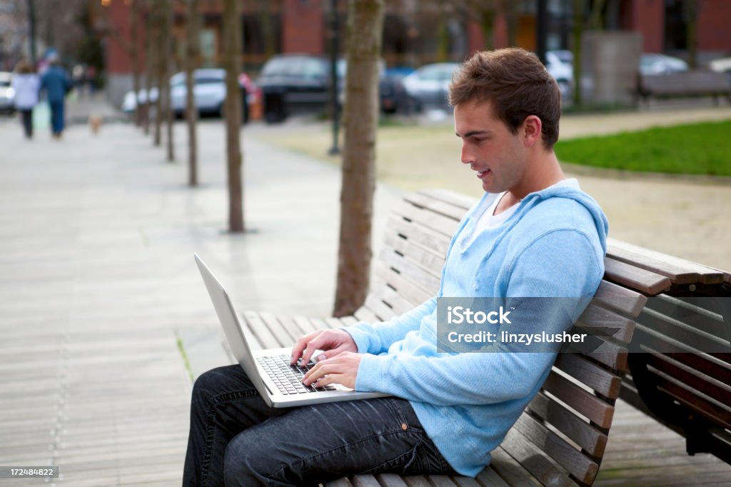 Attraktiver junger Mann mit laptop auf park bench - Lizenzfrei Im Freien Stock-Foto