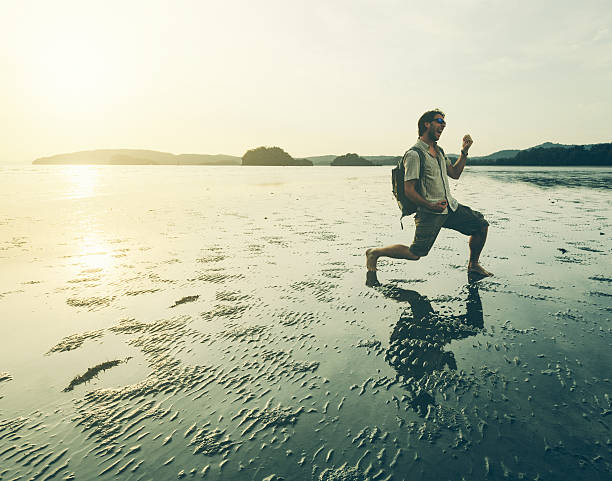 Crazy Man Playing Air Guitar on a Beach Barefoot man with backpack playing air guitar on a remote beach in Thailand at sunset. air guitar stock pictures, royalty-free photos & images