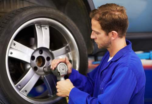 A mechanic tightening the lug nuts of a wheel with a torque wrench